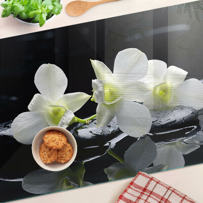 Glas-Schneidebrett mit Orchideenmotiv auf schwarzem Hintergrund