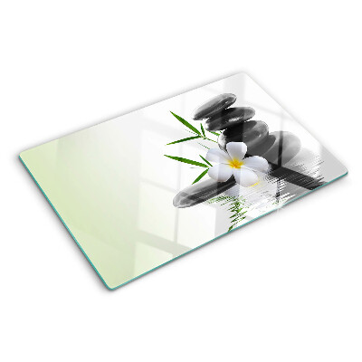 Schneidebrett mit Motiv aus Blumen und Kieselsteinen auf Wasser