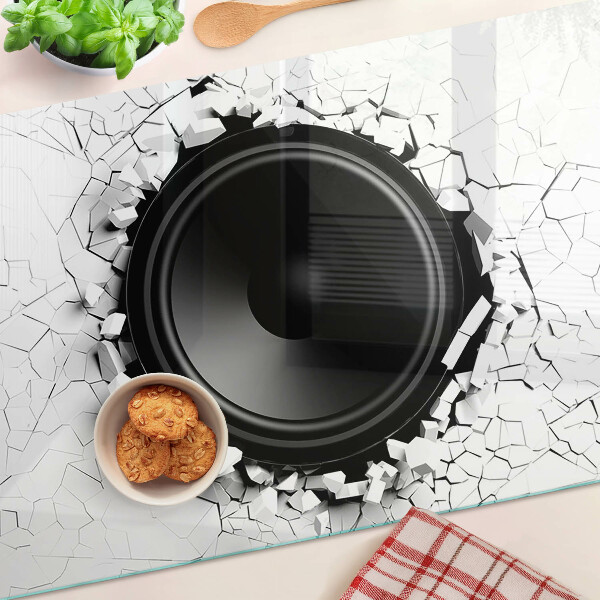 Schneidebrett mit Lautsprecher-Motiv vor einer zerbrochenen Wand