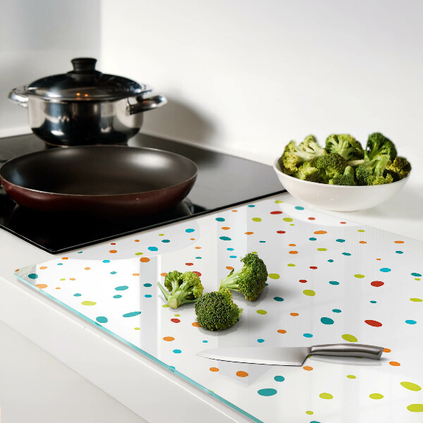 Glas-Schneidebrett mit bunten Punkten auf weißem Hintergrund