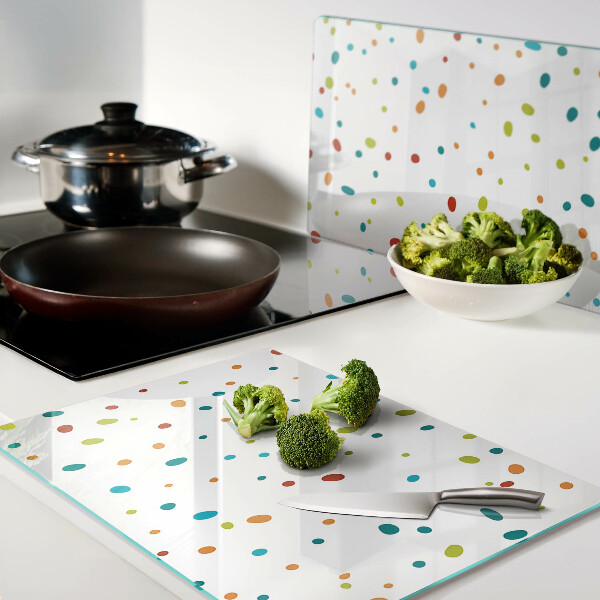 Glas-Schneidebrett mit bunten Punkten auf weißem Hintergrund
