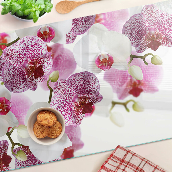 Glas-Schneidebrett mit Orchideen vor einem Fenster als Motiv