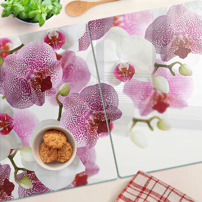 Glas-Schneidebrett mit Orchideen vor einem Fenster als Motiv