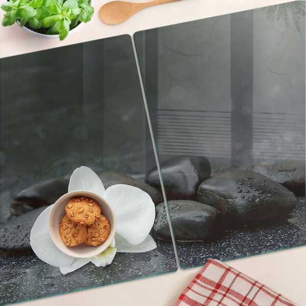 Schneidebrett mit Motiv einer Orchideenblüte auf Steinen