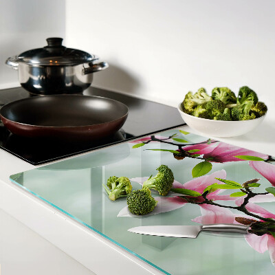 Schneidebrett mit Motiv aus Magnolienblüten vor grünem Hintergrund