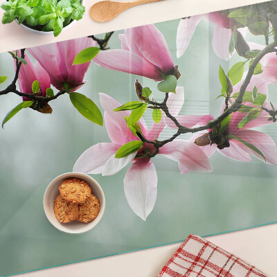 Schneidebrett mit Motiv aus Magnolienblüten vor grünem Hintergrund