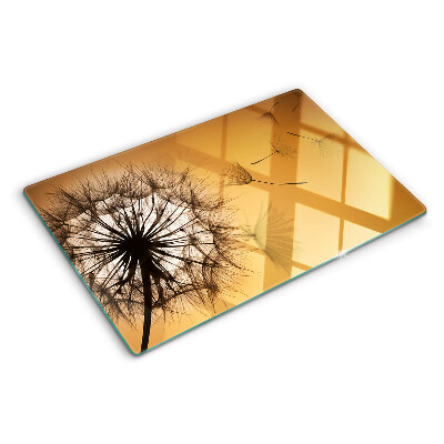 Schneidebrett Glas mit Löwenzahnmotiv vor dem Hintergrund eines Sonnenuntergangs