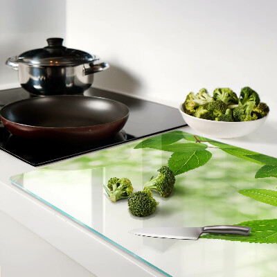 Glas-Schneidebrett mit Blattmotiv vor verschwommenem grünen Hintergrund