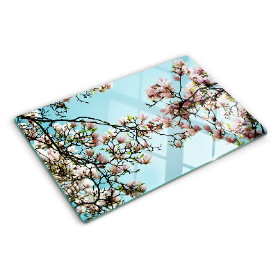 Glas-Schneidebrett mit Magnolienblüten auf blauem Hintergrund