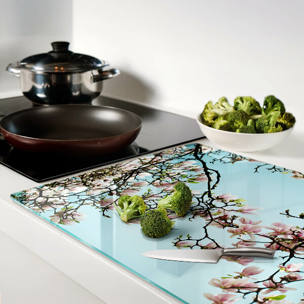 Glas-Schneidebrett mit Magnolienblüten auf blauem Hintergrund