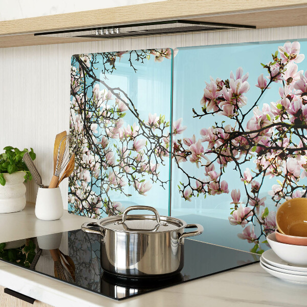 Glas-Schneidebrett mit Magnolienblüten auf blauem Hintergrund