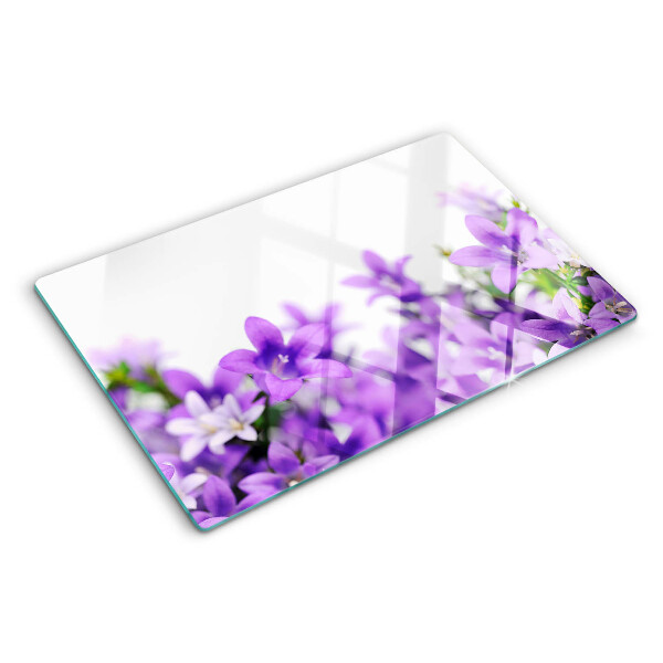 Glas-Schneidebrett mit lila Blumenmuster im Hintergrund