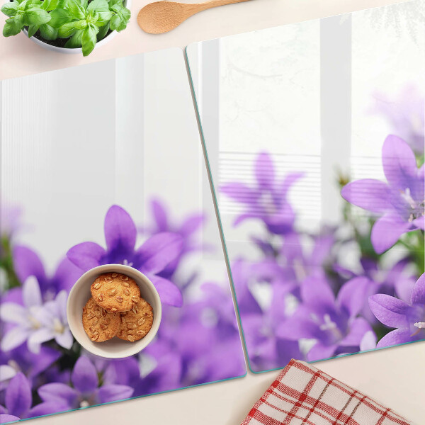 Glas-Schneidebrett mit lila Blumenmuster im Hintergrund
