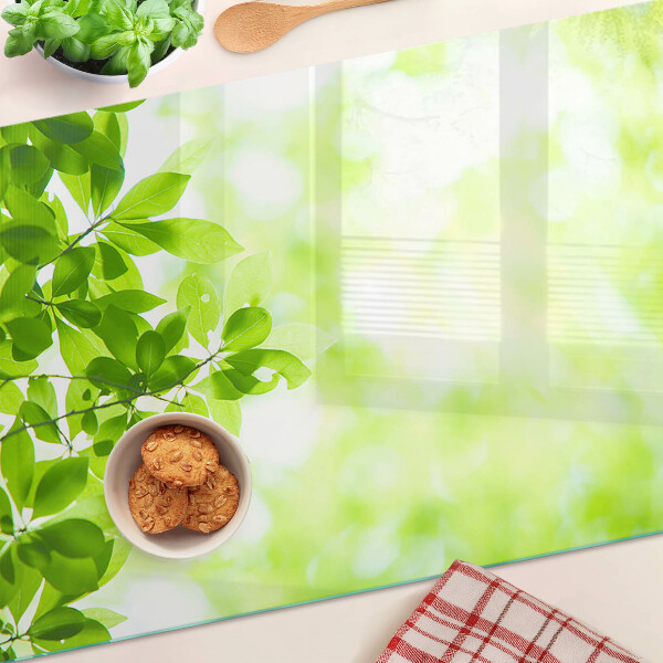 Glas-Schneidebrett mit Motiv grüner Blätter im Licht