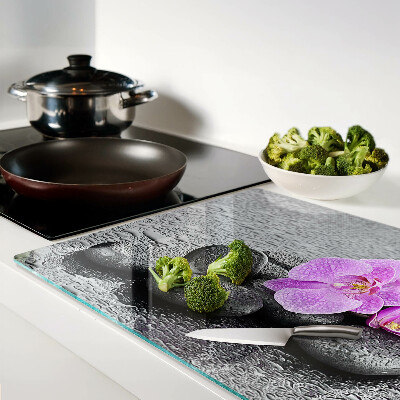 Schneidebrett mit Blumen- und Steindekor vor Wasserhintergrund