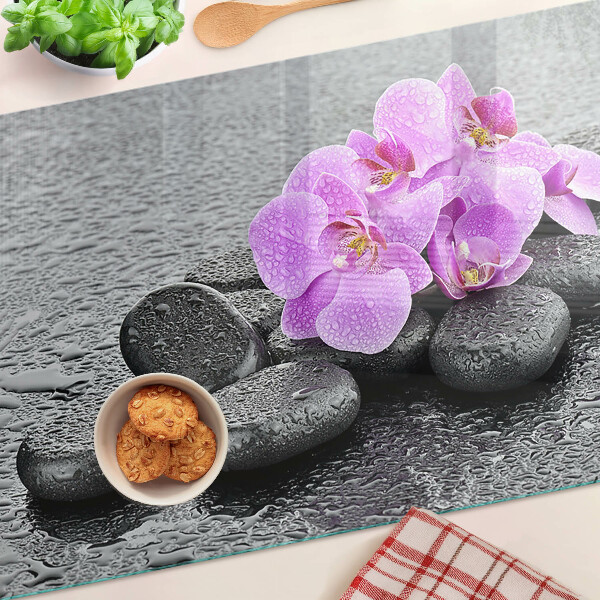 Schneidebrett mit Blumen- und Steindekor vor Wasserhintergrund