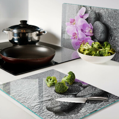 Schneidebrett mit Blumen- und Steindekor vor Wasserhintergrund