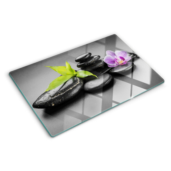 Schneidebrett Glas mit Steinen und Orchideen im Hintergrund