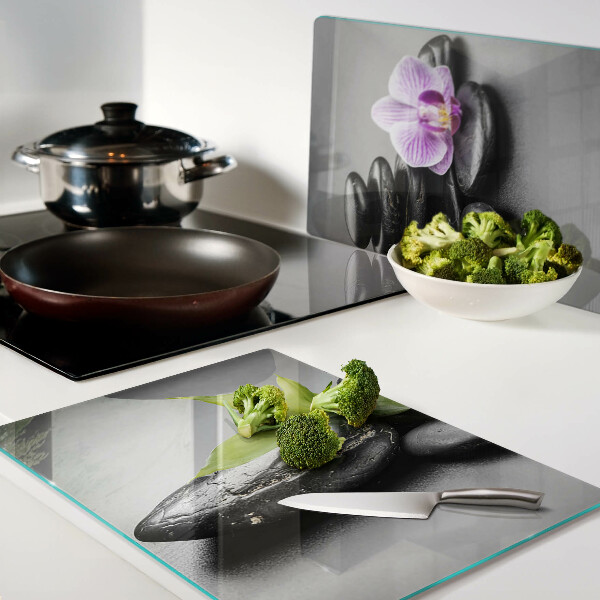 Schneidebrett Glas mit Steinen und Orchideen im Hintergrund