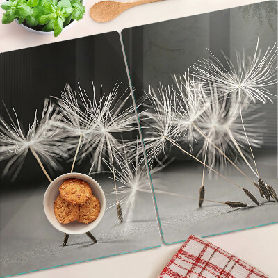 Glas Schneidebrett mit flauschigen Löwenzahnblüten auf einfarbigem Hintergrund