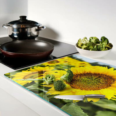 Schneidebrett aus Glas mit Sonnenblumen vor grünem Hintergrund