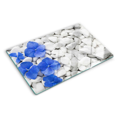Glas-Schneidebrett mit blauem Blumenmotiv auf weißen Steinen