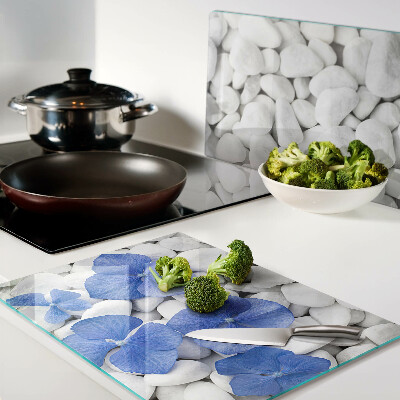 Glas-Schneidebrett mit blauem Blumenmotiv auf weißen Steinen