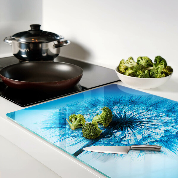 Glas schneidebrett Löwenzahn auf blauem Hintergrund