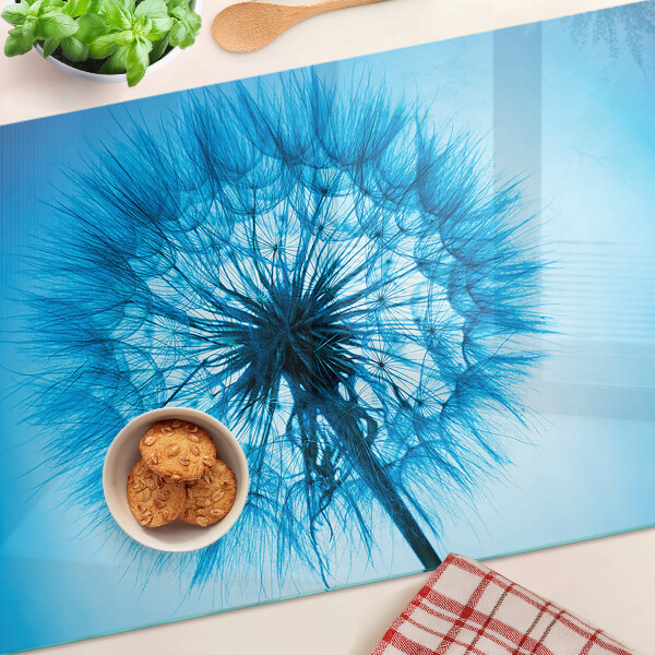 Glas-Schneidebrett mit Löwenzahn-Motiv auf blauem Hintergrund