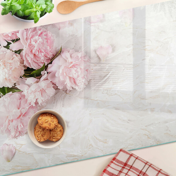 Glas-Schneidebrett mit Pfingstrosen auf marmoriertem Hintergrund