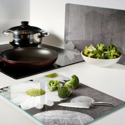 Schneidebrett Glas mit Blumen- und Steinemotiv im Hintergrund