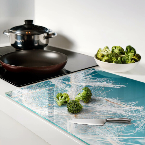 Glas-Schneidebrett mit Löwenzahn-Motiv auf blauem Hintergrund