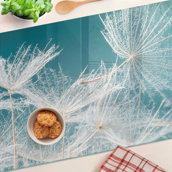 Glas-Schneidebrett mit Löwenzahn-Motiv auf blauem Hintergrund