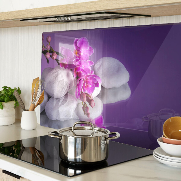 Schneidebrett mit Orchideenblüten vor einem steinernen Hintergrund