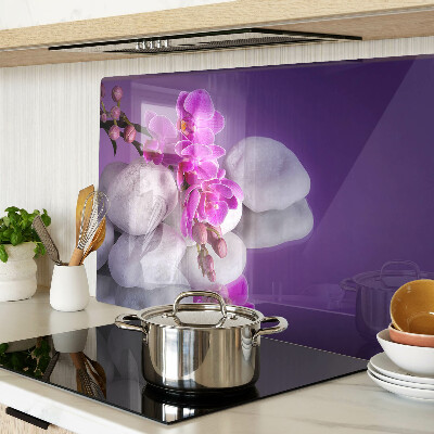 Schneidebrett mit Orchideenblüten vor einem steinernen Hintergrund