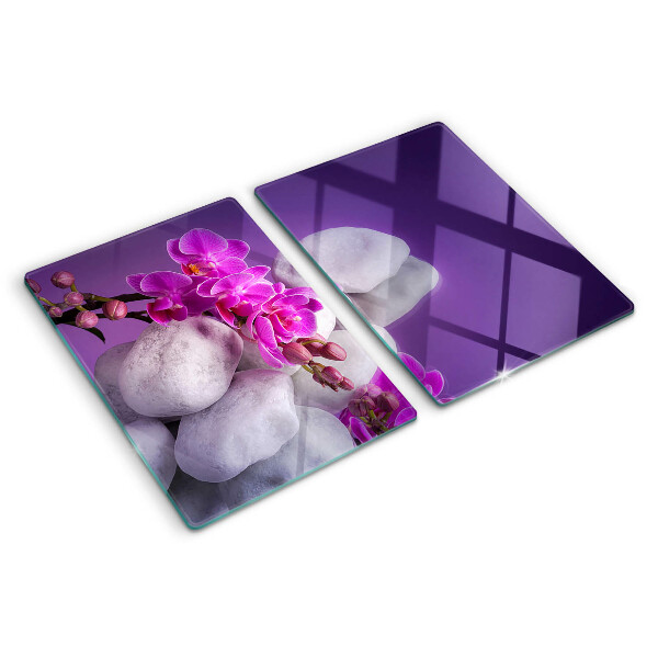 Schneidebrett mit Orchideenblüten vor einem steinernen Hintergrund