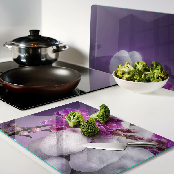 Schneidebrett mit Orchideenblüten vor einem steinernen Hintergrund