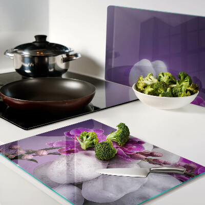 Schneidebrett mit Orchideenblüten vor einem steinernen Hintergrund