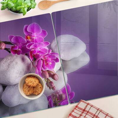 Schneidebrett mit Orchideenblüten vor einem steinernen Hintergrund