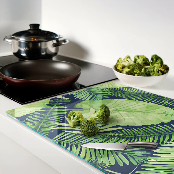 Glas schneidebrett mit tropischen Blättern auf dunklem Hintergrund