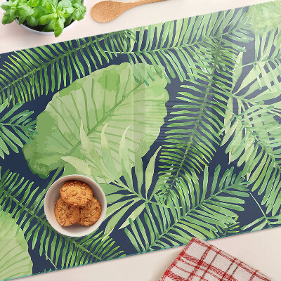 Glas schneidebrett mit tropischen Blättern auf dunklem Hintergrund