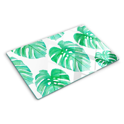 Glas-Schneidebrett mit Monstera-Blättern auf weißem Hintergrund