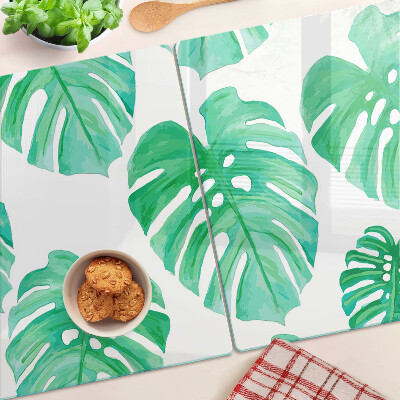 Glas-Schneidebrett mit Monstera-Blättern auf weißem Hintergrund