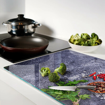 Schneidebrett Glas mit Motiv aus Kräutern und Gewürzen auf steinernem Hintergrund