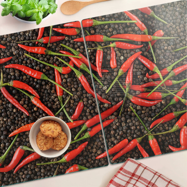 Schneidebrett mit Motiv aus Chilischoten auf schwarzem Pfeffer