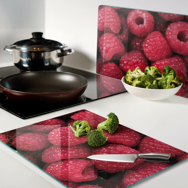 Schneidebrett Glas mit Himbeeren im Hintergrund