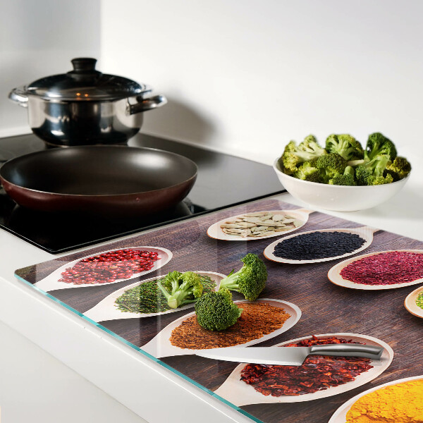 Schneidebrett Glas mit Gewürzen in Löffeln als Dekoration