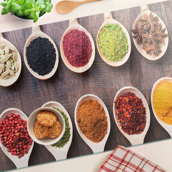 Schneidebrett Glas mit Gewürzen in Löffeln als Dekoration