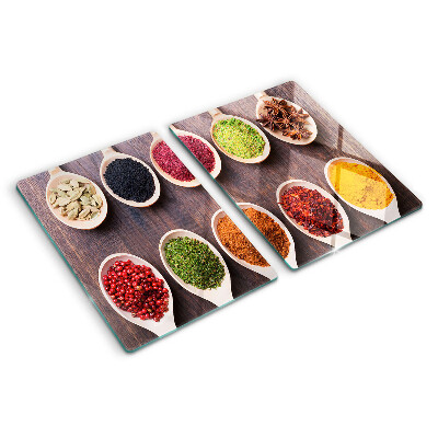 Schneidebrett Glas mit Gewürzen in Löffeln als Dekoration