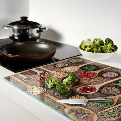 Glas-Schneidebrett mit Motiv aus Gewürzen und Kräutern in Holzlöffeln